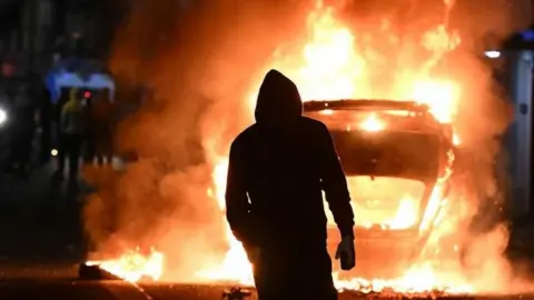 Silhouette of a person against a burning vehicle