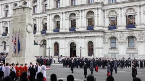 Reuters King Charles stands with other royals and politicians, with a large crowd of onlookers as they attend the Remembrance Sunday Service at the Cenotaph in London. 