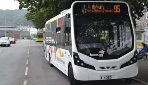 A white single decker Stagecoach bus pictured in Guernsey on a three-lane road on a cloudy day. 