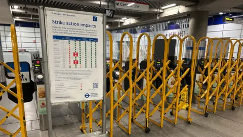 Yellow metal gates pulled across barriers near a 'strike action impacts' sign