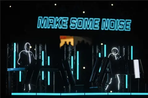 Getty Images DJs stand behind turntables with lights flashing in the Principality Stadium 