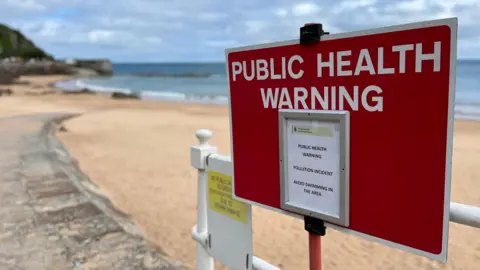 BBC Close up of public health warning sign at beach