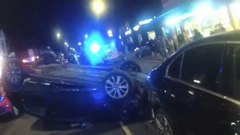 Nottinghamshire Police A black car on its roof with a bright blue light in the background