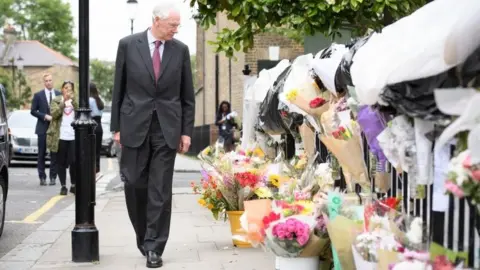 Getty Images Sir Martin Moore-Bick looks at floral tributes