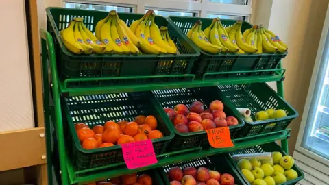 A food stall with fruits such as bananas and apples