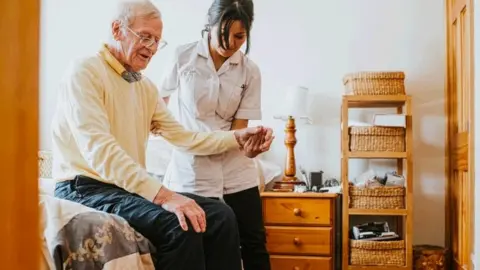 Getty Images a carer helping a patient