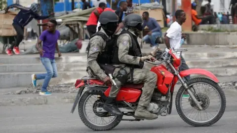 Reuters Protesters and masked men in Haitian National Police uniforms run away during a shooting in Champ de Mars, Port-au-Prince, Haiti February 23, 2020.