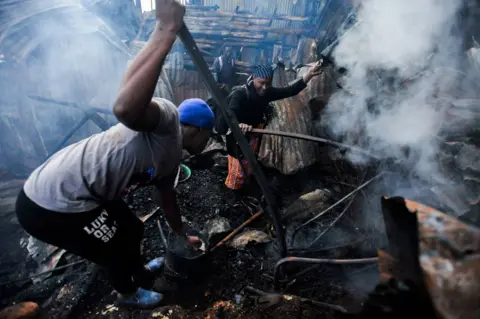 Getty Images Local settlers try to safe their belongings from their burning houses after a fire broke out the slum of Kibagare in Nairobi, Kenya on September 05, 2022.