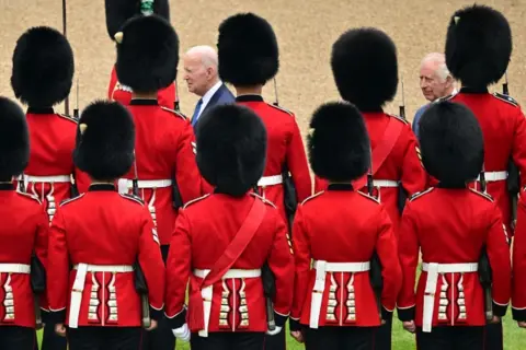 Ben Stansall / AFP US President Joe Biden and Britain's King Charles inspect the Guard of Honour formed by the Welsh Guards, during a ceremonial welcome in the Quadrangle at Windsor Castle
