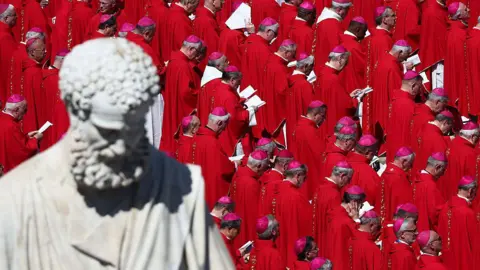 Getty Images Saint Peter's statue appears in the foreground. Dozens of cardinals, wearing red, are seen during the funeral ceremony of Pope Francis at Saint Peter's Square in Vatican on April 26, 2025.