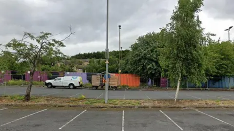 Google Purple and orange shipping containers stored in a car park.