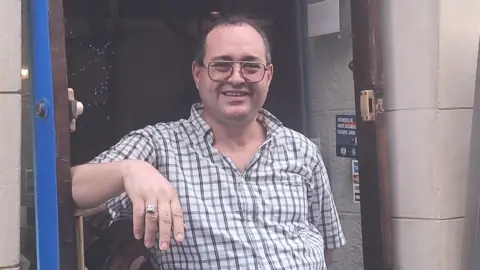 Riad stands in the doorway of his restaurant