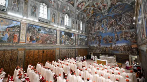 Reuters Cardinals in white robes stand in rows in the Sistine Chapel.
