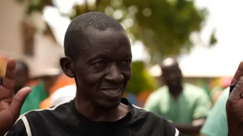 Amensisa Negera / BBC  Daniel Kitambala smiles with one hand raised