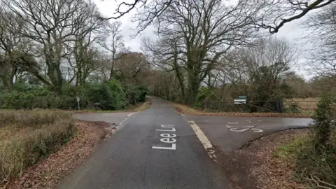 Google A Google street view screenshot of a crossroads of two country lanes with trees on either side.