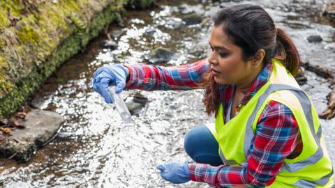 Woman takes water sample from a river 