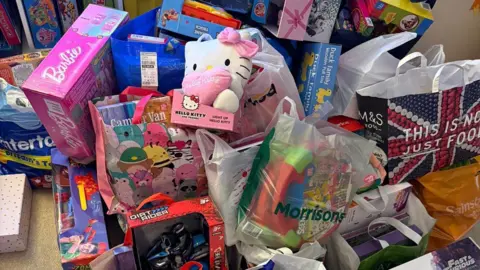 Polly Hurst Colourful boxes of toys placed on the floor.
