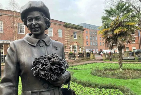 Newcastle-under-Lyme Borough Council The statue is on the left of the photo in the town’s Queens Gardens. Buildings are in the background.