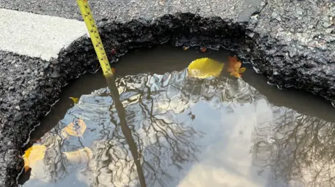 Fixmystreet Tape measure in a pothole reported to Hampshire County Council. 