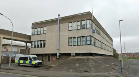 Google Washington Police Station. It is a light grey three-storey building. A police van is parked outside. 