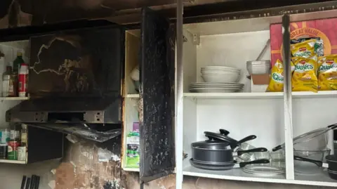 A blackened kitchen cabinet and hob.