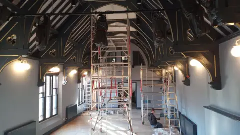 Kirkgate Centre The interior of the Victorian building - which has a high, arched ceiling with visible wooden beams - during the project. Scaffolding reaches to the roof and people can be seen working.