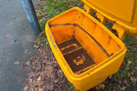 An empty yellow grit bin.