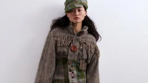 Paul Sunga and Nicky Chan A woman model wearing one of Alexandra's designs created for the Redress Design Award. Top, skirt and jacket are made from undyed or naturally dyed woollen tweed and offcuts rescued from a closing blanket mill.