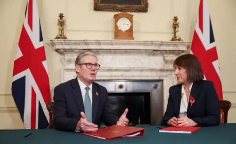 A chanceler da Getty Images, Rachel Reeves, senta-se a uma mesa em Downing Street com o primeiro-ministro Keir Starmer na véspera da adoção do primeiro orçamento do governo trabalhista