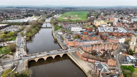 An aerial shot of Worcester with a large river separating two sides of the city along with a bridge. 