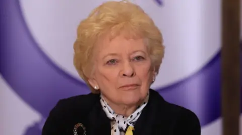 Nuala O'Loan in black jacket with blonde hair.