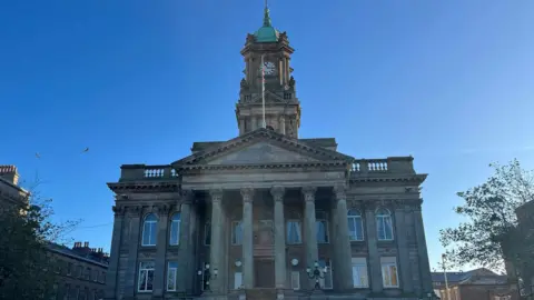 BBC Birkenhead Town Hall including the clock tower. The neoclassical building  features six columns in front of the entrance. 