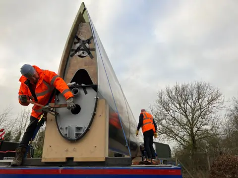 Men attaching a sail to a lorry