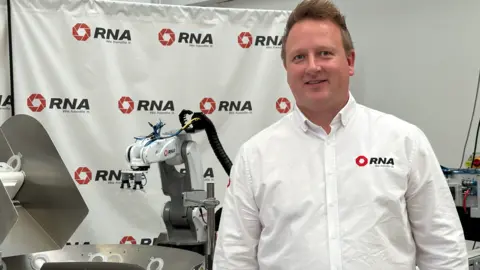 RNA Man in white shirt standing in front of industrial equipment