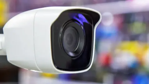 Close-up of a CCTV with a blurred background of goods on shop shelves