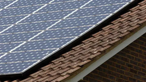 A building's slate roof where solar panels have been installed. 