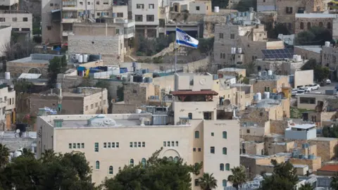 Reuters An Israeli flag flies over an Israeli settlement in the old city of Hebron, in the occupied West Bank (9 February 2026)