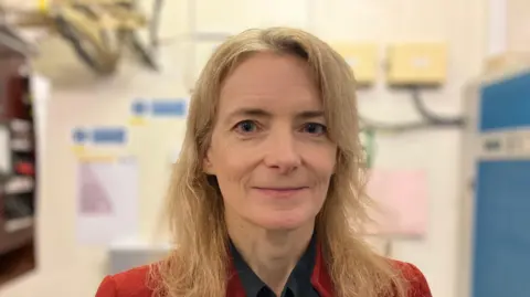 UK telecoms minister Liz Lloyd who has long blonde hair and wears a red jacket.