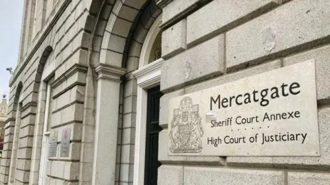 The exterior of the High Court in Aberdeen. A sign on a pale grey building reads Mercatgate / Sheriff Court Annexe / High Court of Justiciary