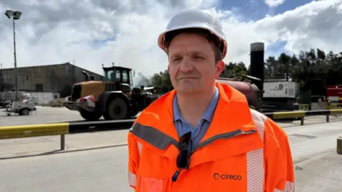 A man with a hard hat and hi-vis jacket that says Cireco stands outside at a landfill site