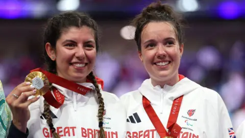 Getty Images Two sportswomen stand side by side.