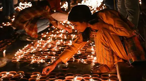 Getty Images People light earthen lamps on the banks of the Sarayu River during a program on the eve of Diwali on November 11, 2023, Ayodhya