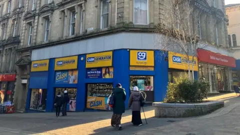 An old-fashioned building on the corner of a high street, with a Cash Generator store on the ground floor.