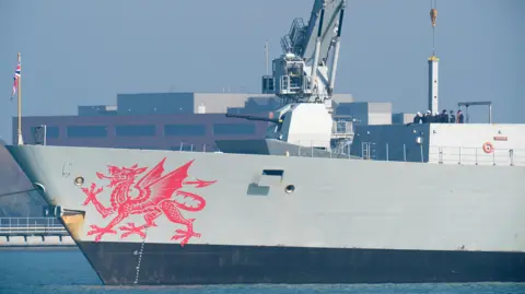 PA Media A grey warship is seen with a large red dragon painted on the bow.