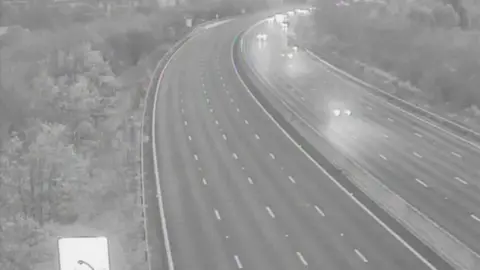 A picture from a camera of the M23, showing one carriageway completely empty, while the other one has cars travelling towards the camera