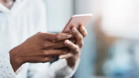 Getty Images Woman holding mobile phone