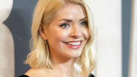 Getty Images Holly Willoughby, with shoulder-length blonde wavy hair, smiles out of the camera