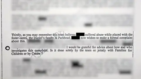 A scan of a letter - most of which is blurred and redacted. The visible text reads: "As you may remember, this team believes [redacted] suffered abuse while placed with the foster carers, the Daniels family in Parkhead. [redacted] now wishes to make a formal complaint about this... I would be grateful for advice about how and who investigates this complaint. Is it done solely by the team of jointly with Families for Children or by Centre?"
