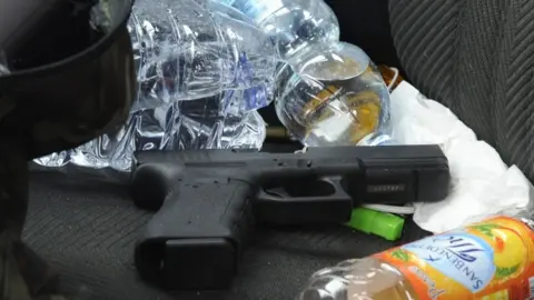 AFP A handgun on the seat of a black Alfa Romeo used by a man suspected of wounding several foreign nationals in a drive-by shooting in Macerata, 3 February