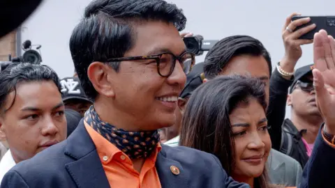 Reuters Madagascar's President and a presidential candidate Andry Rajoelina flanked by his wife Mialy Rajoelina as he arrives to cast his ballot at a polling station, during the presidential election in Ambatobe, Antananarivo, Madagascar November 16, 2023.